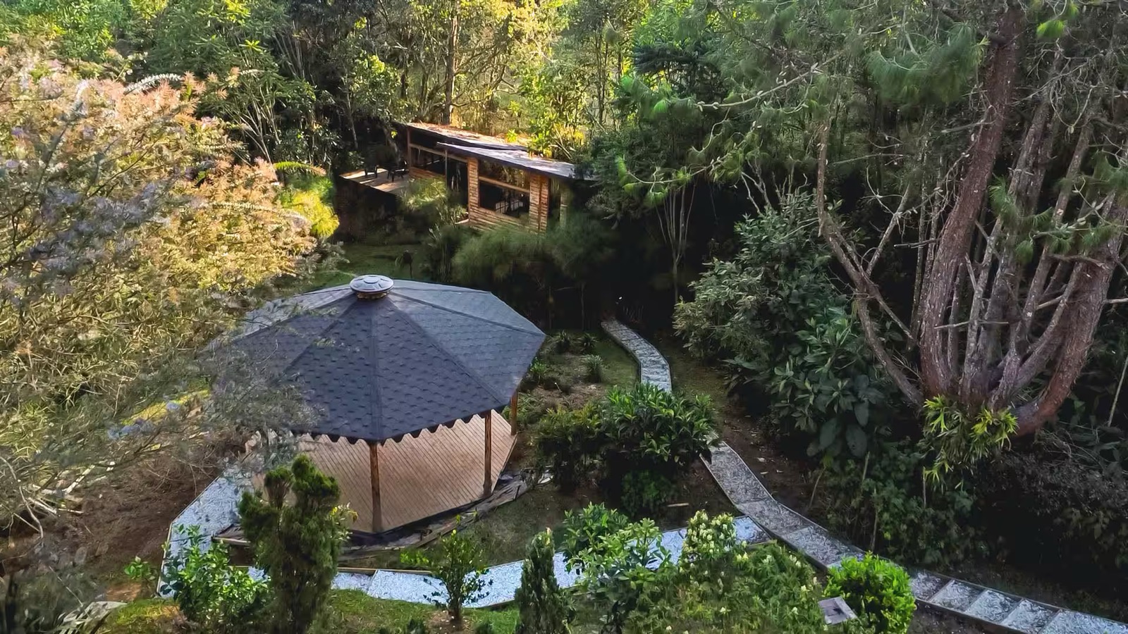 Jardín de Casa Ilusión con cobertizo de madera y pinos al fondo