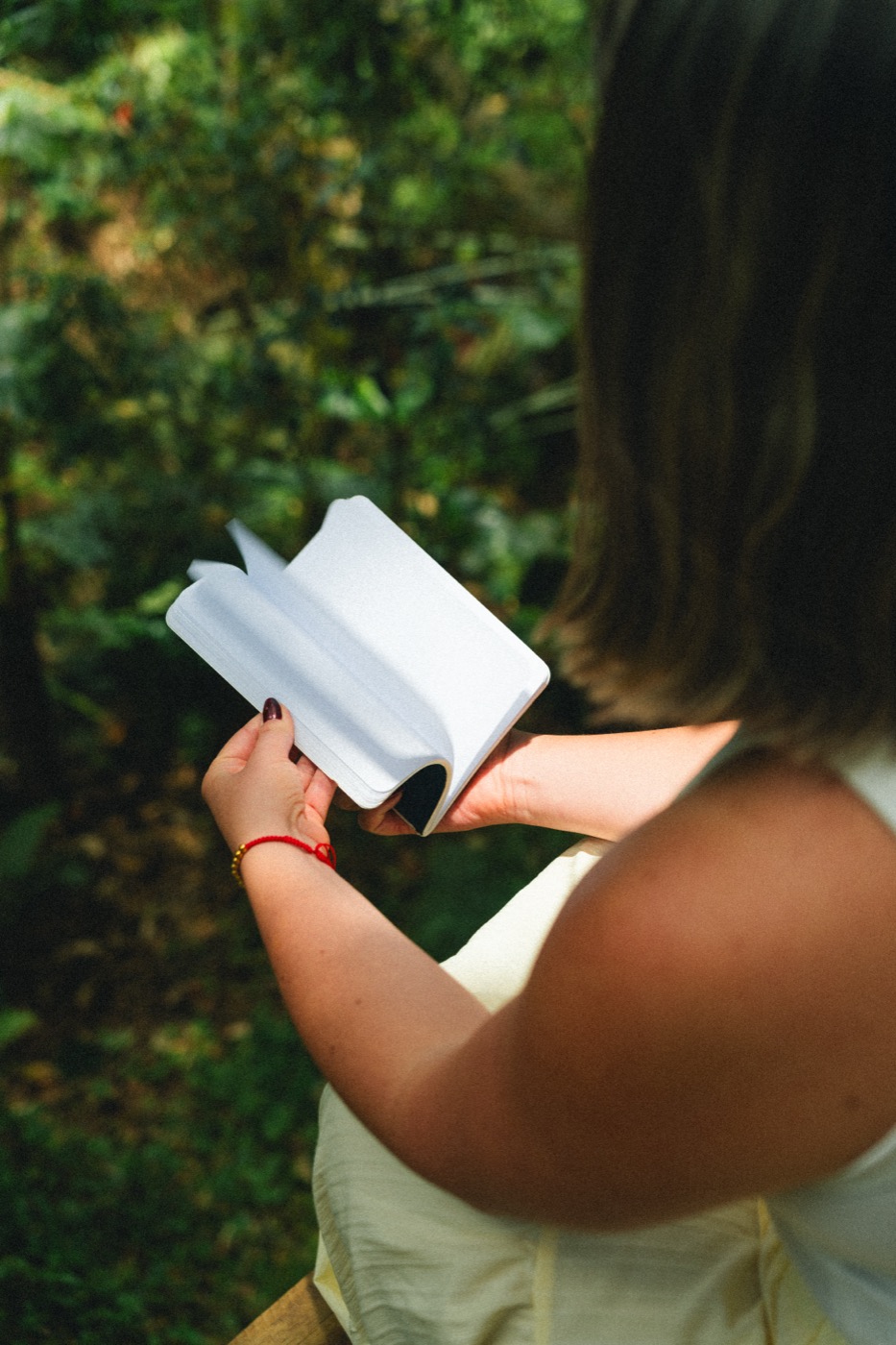 Manos sosteniendo una libreta abierta en el bosque